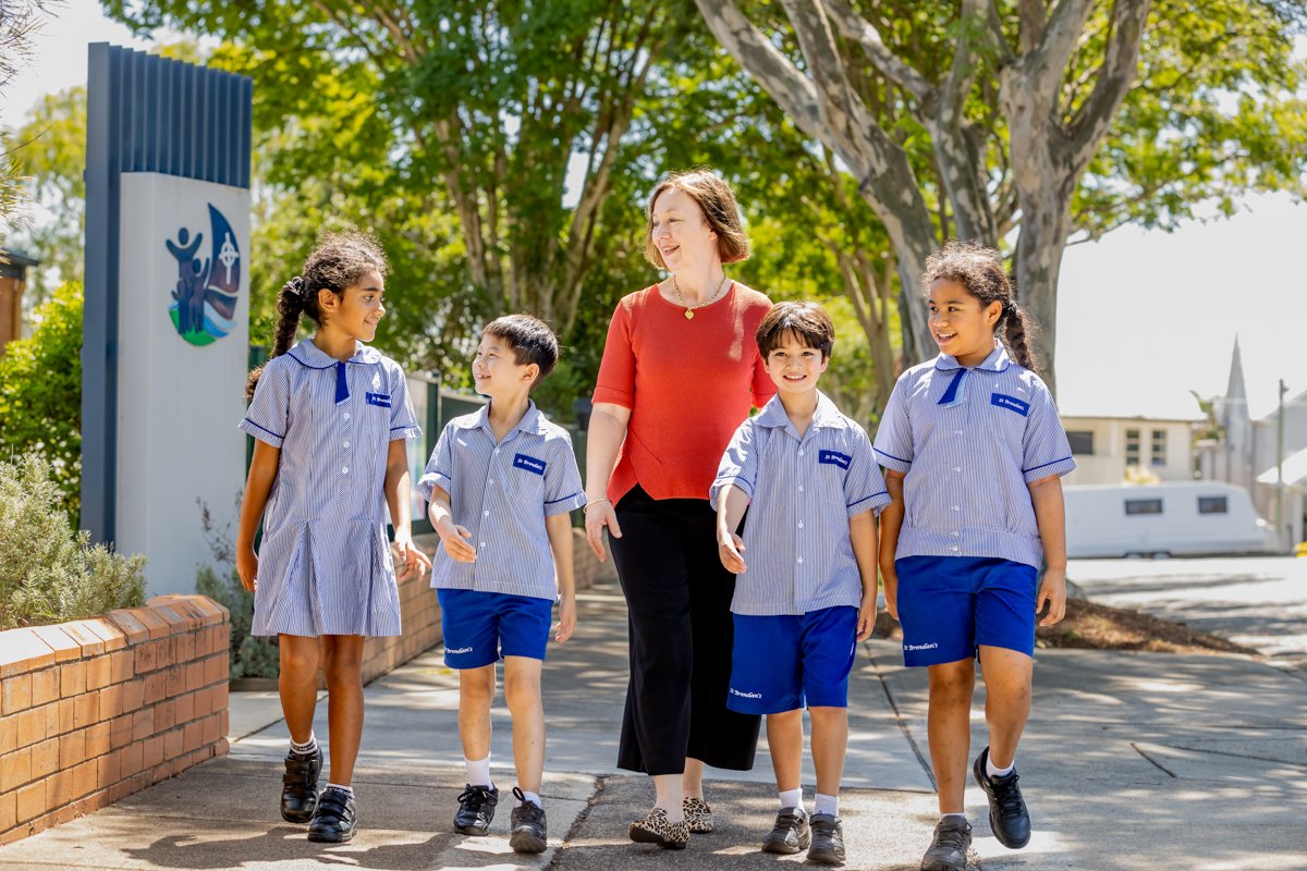 Principal Mrs Cathie Caldwell walking with students in school uniform along pathway outside school entrance