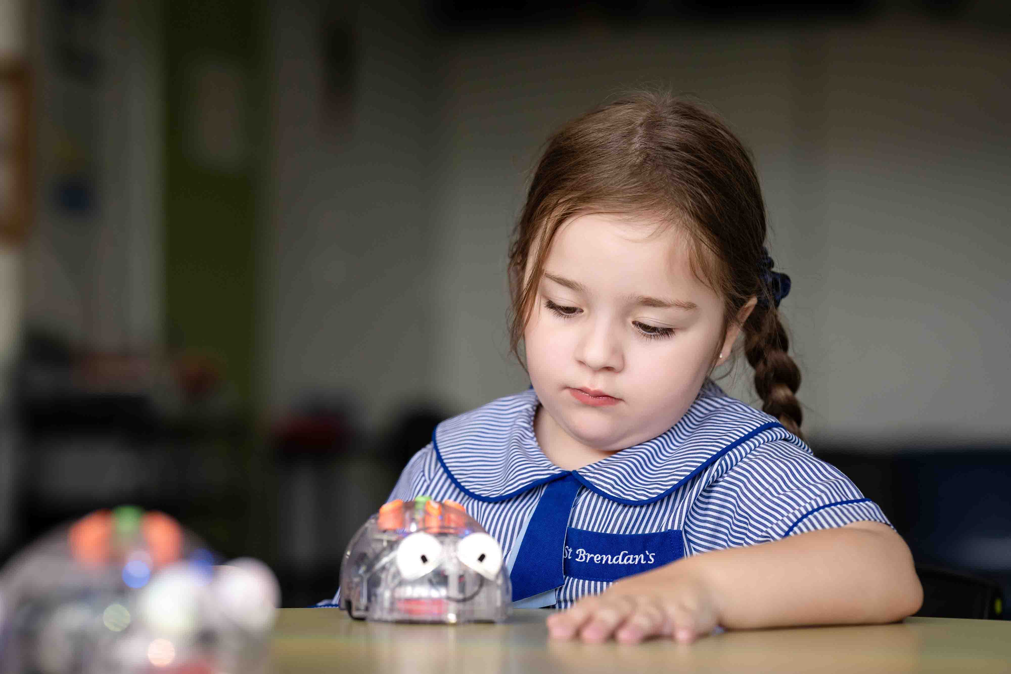 Student exploring early robotics activity with programmable toy during classroom learning