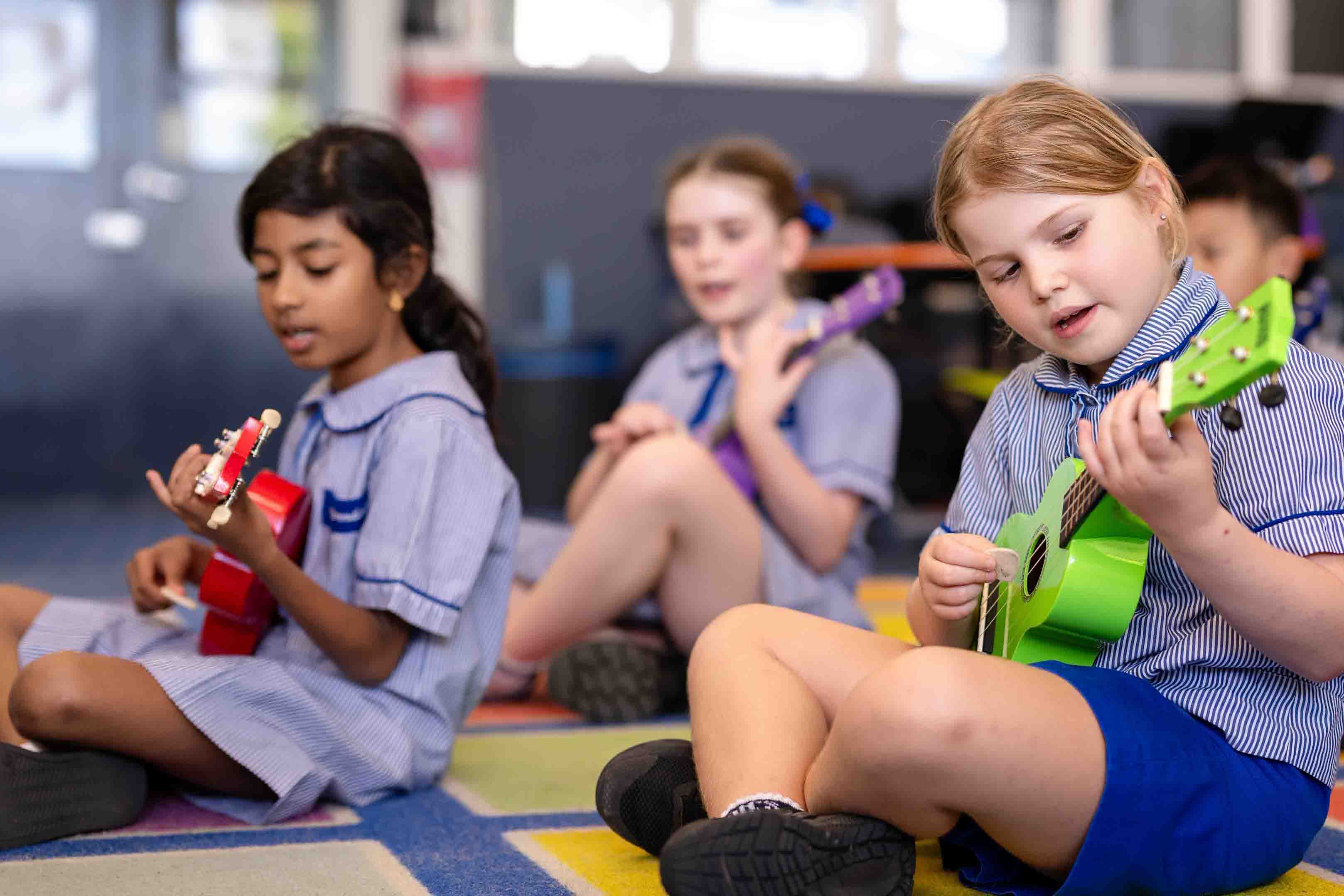 Students playing ukulele instruments together during classroom music lesson